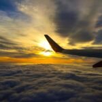 Airplane wing above clouds at sunset
